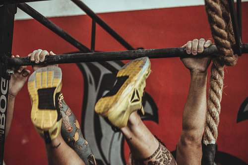brazil person wearing yellow-and-black Reebok low-top athletic shoes hanging on pull-up bar workout